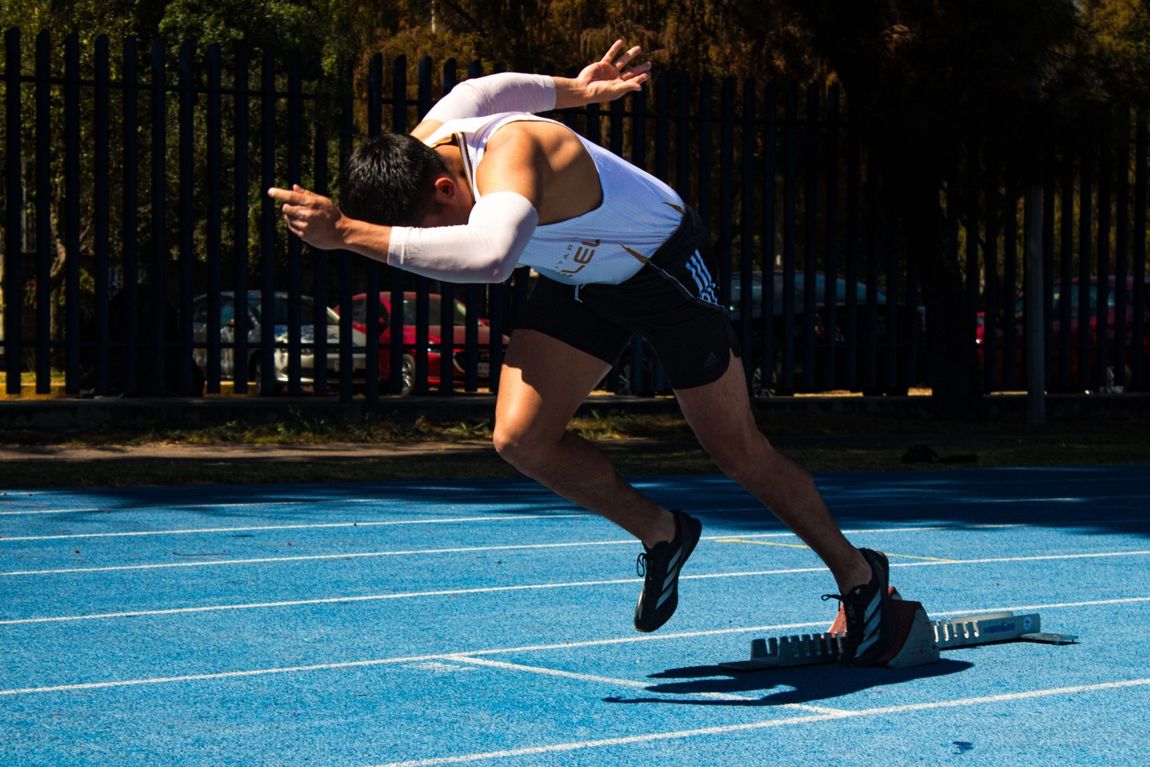 Sprinter driving out of the starting blocks on a blue track